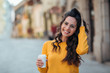 © bnenin - Beautiful casual brunette with coffee to go in the city street, smiling at camera.
