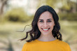 © bnenin - Headshot of a young brunette woman with a toothy smile on a light outdoor background.