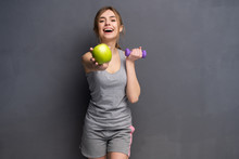 Sporty Fit Woman Holding Dumbbells Weights In One And Apple Fruit In Another Hand. Fitness And Healthy Dieting Concept.