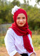© ShutterChiller - Women muslim, women islamic,wearing a red fabric head covering adorn with white fabric flowers wear shirt white sit poses photography on the Stump before to ramadan month.