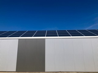 Sustainability: A modern iron warehouse covered by solar panels against great blue sky