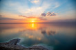 Amazing sunset over Dead sea, view from Jordan to Israel and Mountains of Judea. Madaba governorate and Karak governorate. Reflection of sun, skies and clouds. Salty beach, salt on Dead sea coast