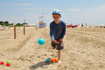 young boy playing boules with colorful balls