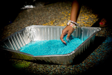 Child hand taking coloured raw rice grains creating traditional Indian  artwork 