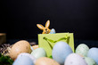 Small Easter bunny peeking from gift bag with colorful easter eggs