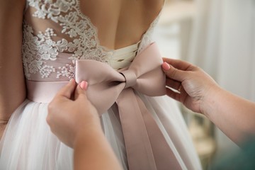 Mom pulls up a big bow on a wedding dress