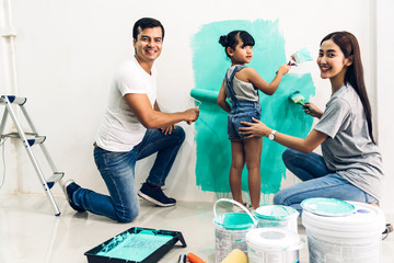 Wall Mural - Happy family using a paint roller and painting walls in their new home