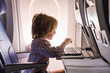 © Marc Romanelli - 5 year old boy on airplane, using  a laptop