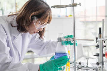 Wall Mural - a young asian woman scientist working in laboratory with test tube microscope and solutions.