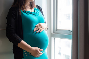 Beautiful happy asian pregnant women standing in room by window