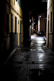 Fototapeta Uliczki - Night urban scene on a wet cobble stone street in Pisa, Italy
