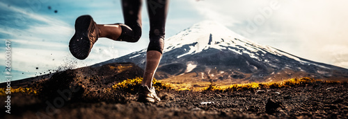 Fotografía Legs of the woman running on the trail with volcano on the background