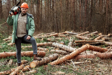 Logging, Worker in a protective suit with a chainsaw. Cutting down trees, forest destruction. The concept of industrial destruction of trees, causing harm to the environment.