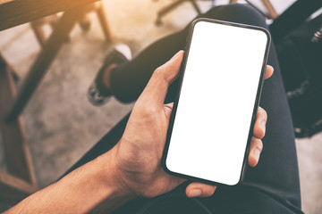 mockup image of a man's hand holding and using black mobile phone with blank white screen while sitt