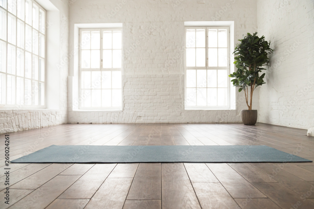 Unrolled yoga mat on wooden floor in yoga studio - obrazy, fototapety, plakaty 