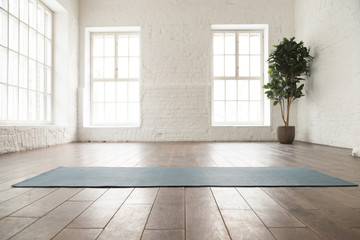 unrolled yoga mat on wooden floor in yoga studio