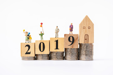 Miniature people family standing on coins stacks with word text 2019 and house model on the top stack.  concepts. Concept for property ladder, mortgage,real estate investment.