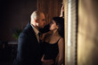 © borislav15 - A bald man in a black suit pressed a beautiful dark-haired girl against the wall, the girl holding on to a tie. Horizontal photography