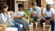 © fizkes - Diverse young friends using social media on phones in cafe