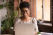 © fizkes - Happy mixed race woman student using laptop working studying indoor