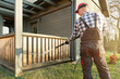 © artursfoto - Man cleaning terrace with a power washer - high water pressure cleaner on wooden terrace railing
