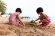 Leinwandbild Motiv Asian Chinese little sisters playing sand at beach