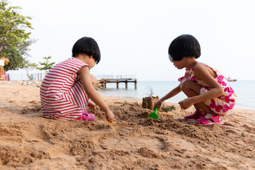 Wall Mural - Asian Chinese little sisters playing sand at beach