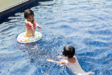 Wall Mural - Asian Little Chinese Sisters Playing in Swimming Pool