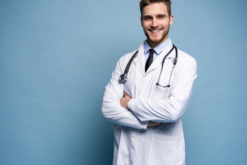 Wall Mural - Portrait of confident young medical doctor on blue background.