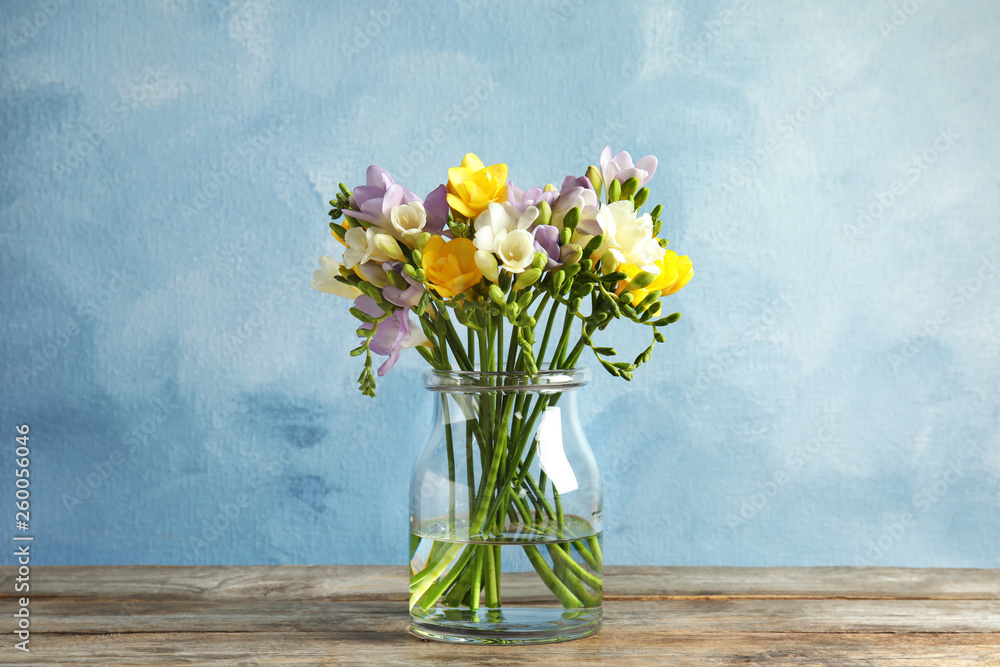 Bouquet of fresh freesia flowers in glass vase on table - obrazy, fototapety, plakaty 