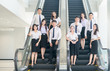 © kwanchaichaiudom - Smart young students standing together on escalator