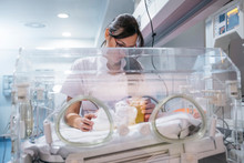 Female Doctor Examining Newborn Baby In Incubator