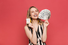 Beautiful Amazing Young Woman Posing Isolated Over Red Coral Background Holding Credit Card And Money.