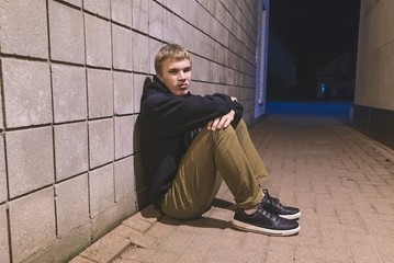 Wall Mural - Sad teen sitting in an alleyway all alone at night.