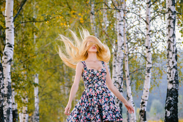 Wall Mural - An attractive girl with fluttering hair and a short dress walks in the Park.