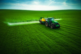 Fototapeta  - Aerial view of farming tractor plowing and spraying on field