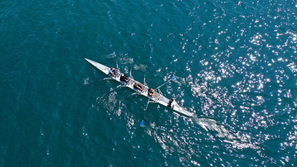 Wall Mural - Aerial drone bird's eye view of sport canoe operated by team of young men and women in open ocean sea