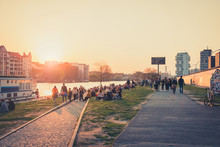 People Enjoying Sunset At River Next To The Berlin Wall / East Side Gallery  In Berlin, Germany