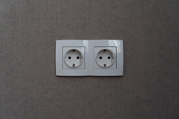 two white power sockets with frame on dark grey wall as a background