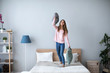 © BestForYou - Young cheerful woman having fun with pillows on the bed at home.