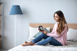 © BestForYou - Smiling young woman lying awake in bed with alarm clock, good morning.