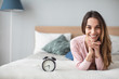 © BestForYou - Beautiful smiling woman with alarm clock on the bed at home.