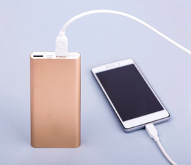 Smartphone charging with power bank and phone on gray background