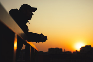 Silhouette of dreaming man in city sunset looks forward at cityscape