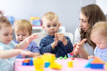 woman teaches children modeling plasticine in day care center
