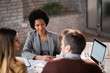 © Drazen - Smiling black financial consultant talking to a couple during a meeting in her office.