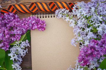 Wall Mural - May 9 victory Day. Branches of blooming lilac for viewing, military cap, St. George's ribbon and a white paper crane on a wooden background / Cranes-the memory of the dead soldiers.Concept of memory.