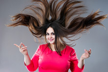 Plus Size Model With Long Hair Blowing In The Wind, Brunette Fat Woman On Gray Background, Body Positive Concept