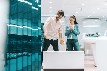 Canvas Print - Happy couple standing at tech store and looking at new plasma tv in box they bought.