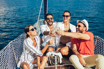 Wall Mural - Smiling friends with glasses of champagne on yacht. Vacation, travel, sea, friendship and people concept